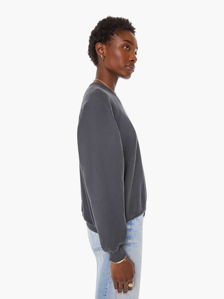Side view of a woman in a faded black oversized raglan sweatshirt with a crewneck, ribbed hems and a slightly cropped fit.