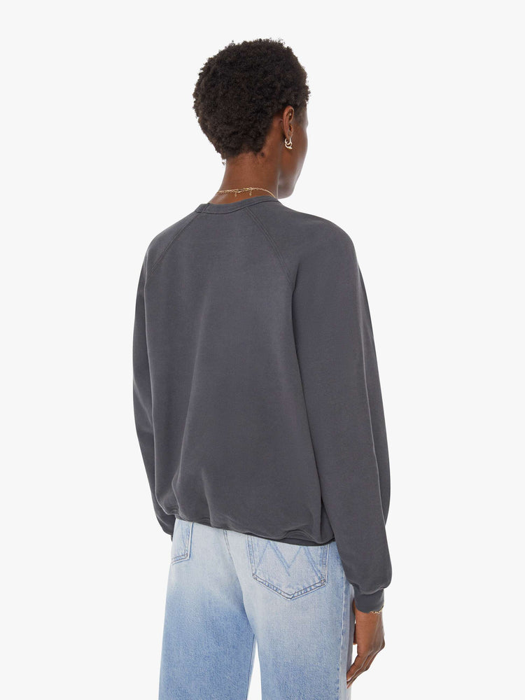 Back view of a woman in a faded black oversized raglan sweatshirt with a crewneck, ribbed hems and a slightly cropped fit.