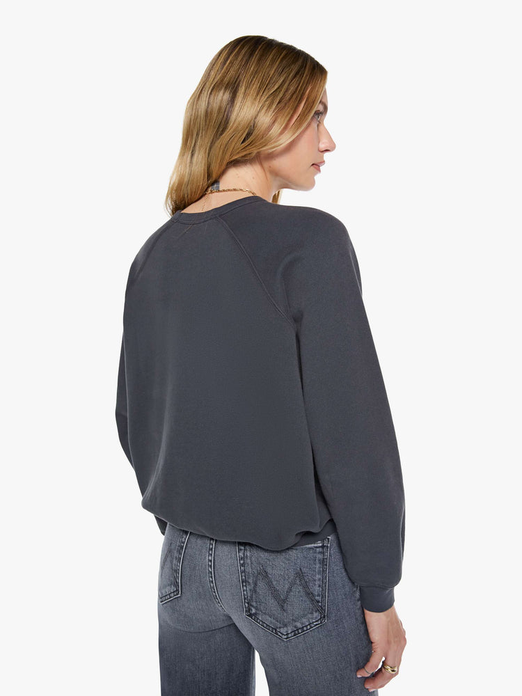 Back view of a woman in a faded black oversized raglan sweatshirt with a crewneck, ribbed hems and a slightly cropped fit.