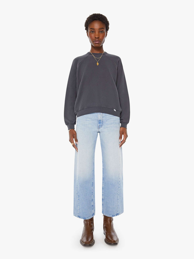 Full body view of a woman in a faded black oversized raglan sweatshirt with a crewneck, ribbed hems and a slightly cropped fit.