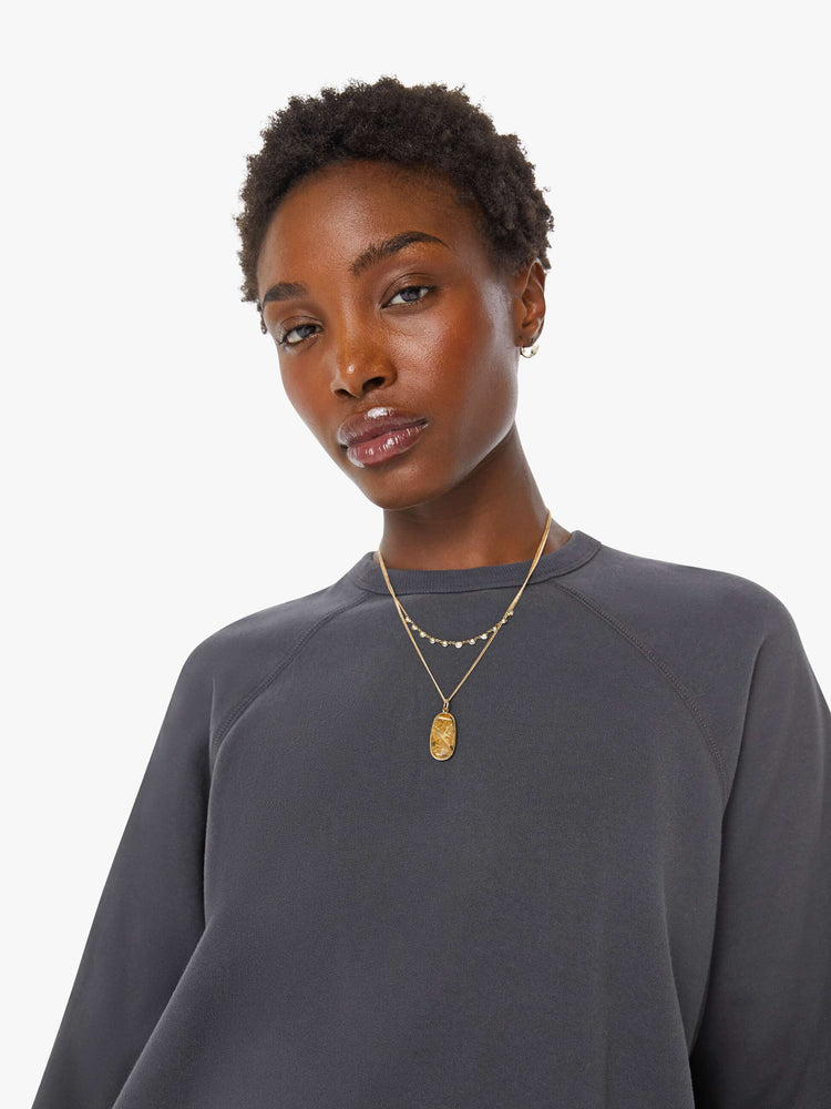 Close up view of a woman in a faded black oversized raglan sweatshirt with a crewneck, ribbed hems and a slightly cropped fit.