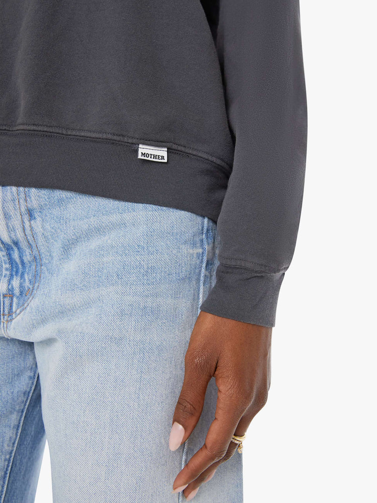Close up view of a woman in a faded black oversized raglan sweatshirt with a crewneck, ribbed hems and a slightly cropped fit.