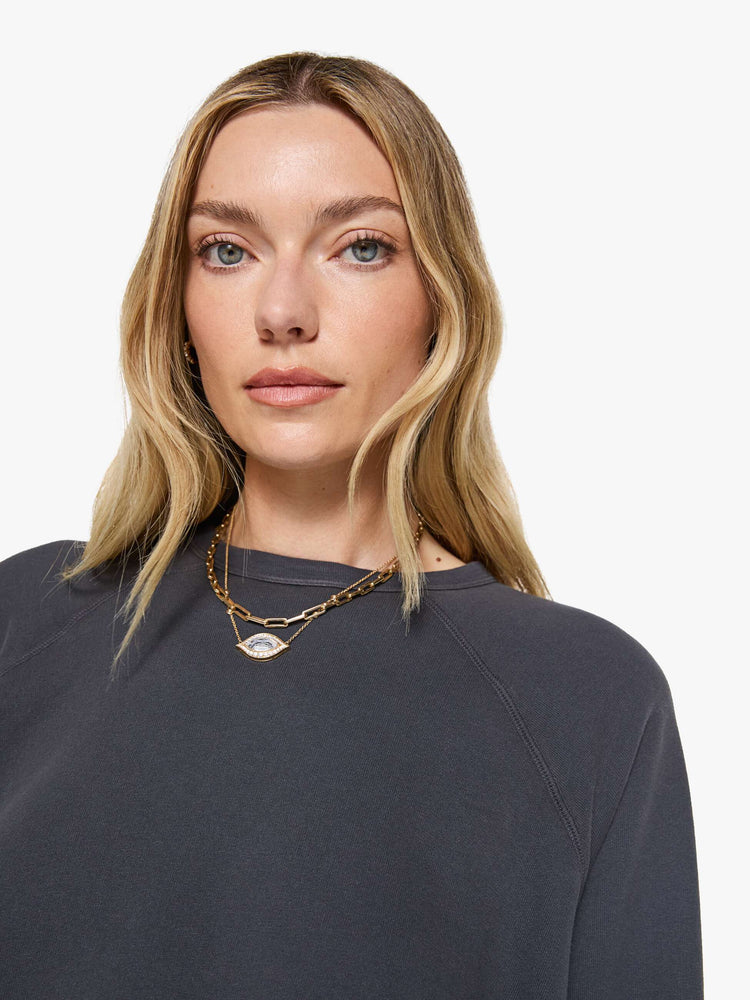 Close up view of a woman in a faded black oversized raglan sweatshirt with a crewneck, ribbed hems and a slightly cropped fit.