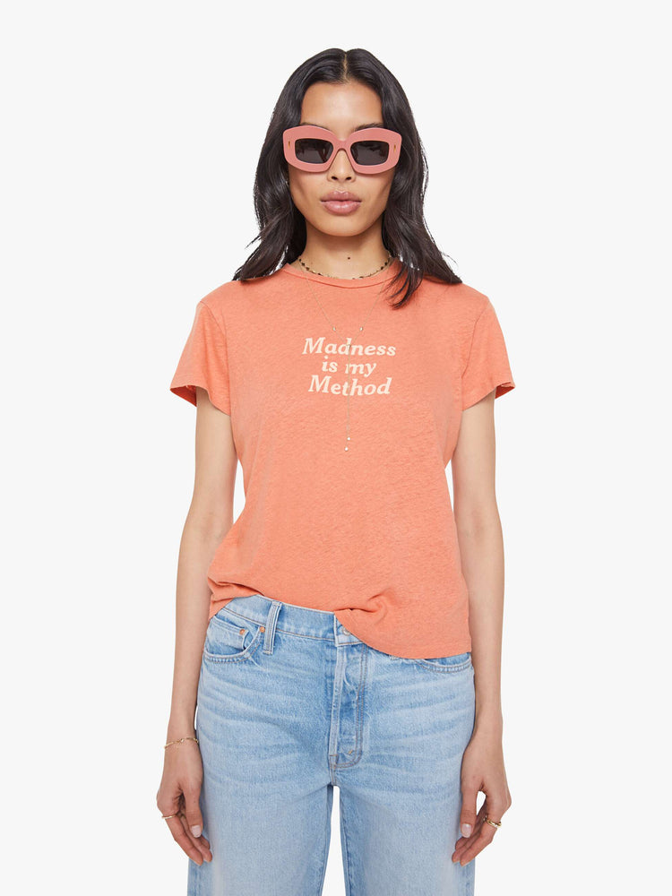 Front view of a woman in a faded orange tee with a cream text graphic on the front.