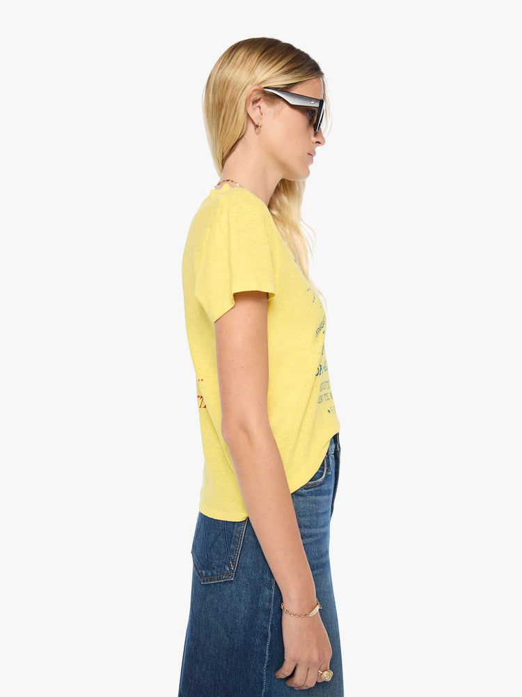 Side view of a woman in a yellow tee with a cosmic music festival graphic in blue on the front and red on the back.