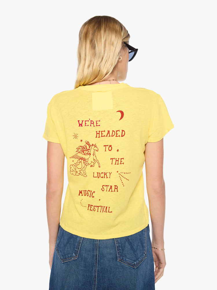 Back view of a woman in a yellow tee with a cosmic music festival graphic in blue on the front and red on the back.