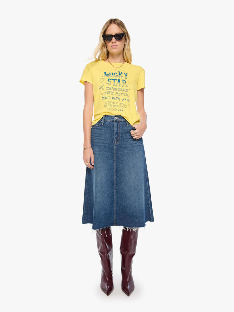 Full body view of a woman in a yellow tee with a cosmic music festival graphic in blue on the front and red on the back.