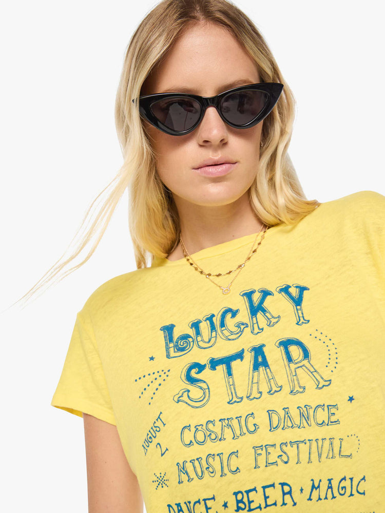 Close up view of a woman in a yellow tee with a cosmic music festival graphic in blue on the front and red on the back.