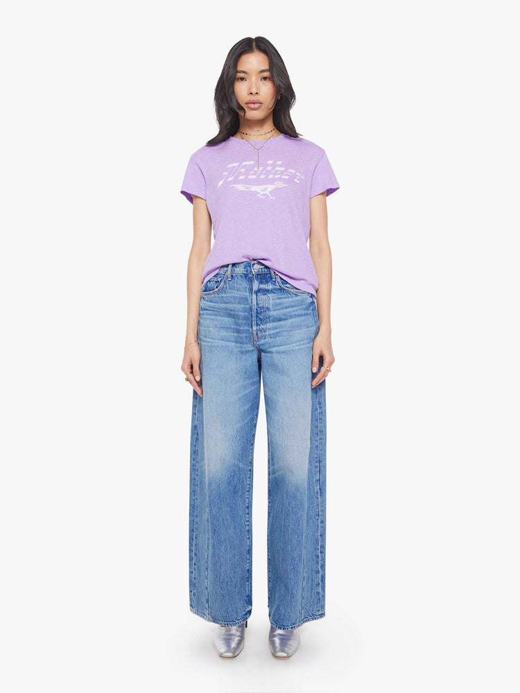Full body view of a woman in a slim fit lavender tee with white faded graphic.