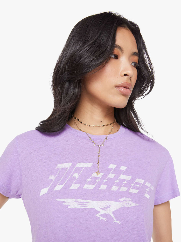 Close up view of a woman in a slim fit lavender tee with white faded graphic.