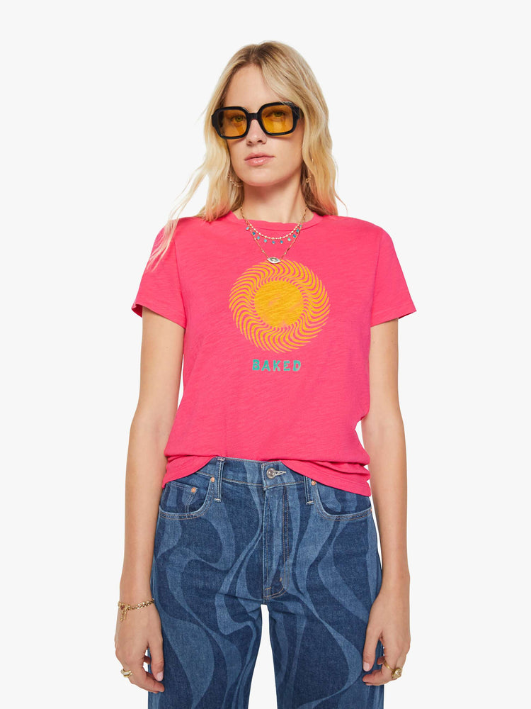Front view of a woman in a pink tee with golden sun graphic and text in teal on the front.