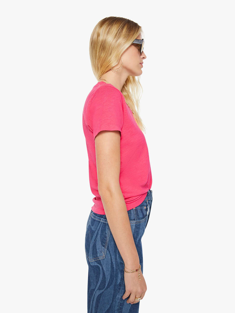 Side view of a woman in a pink tee with golden sun graphic and text in teal on the front.
