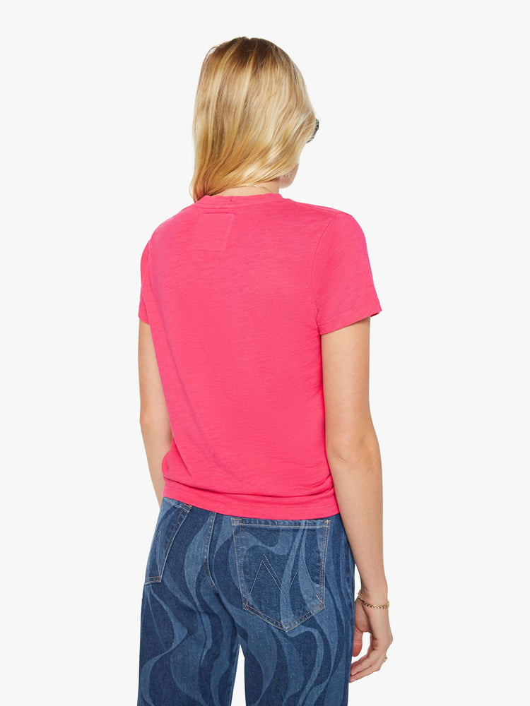 Back view of a woman in a pink tee with golden sun graphic and text in teal on the front.