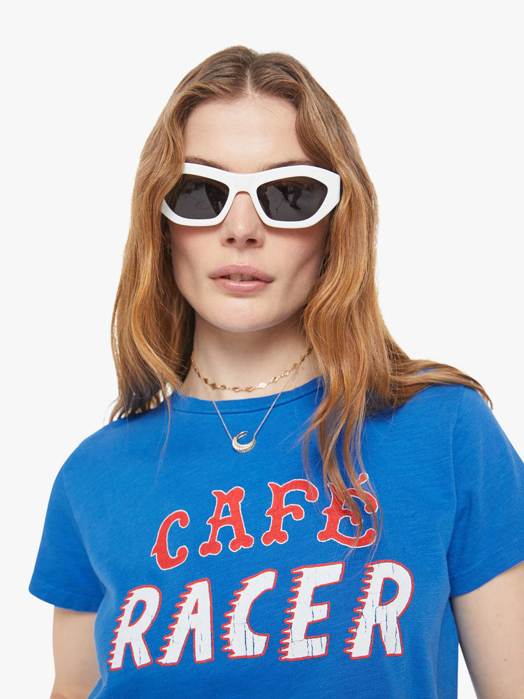 Close up view of a woman in a blue tee with a red and white text graphic on the front.