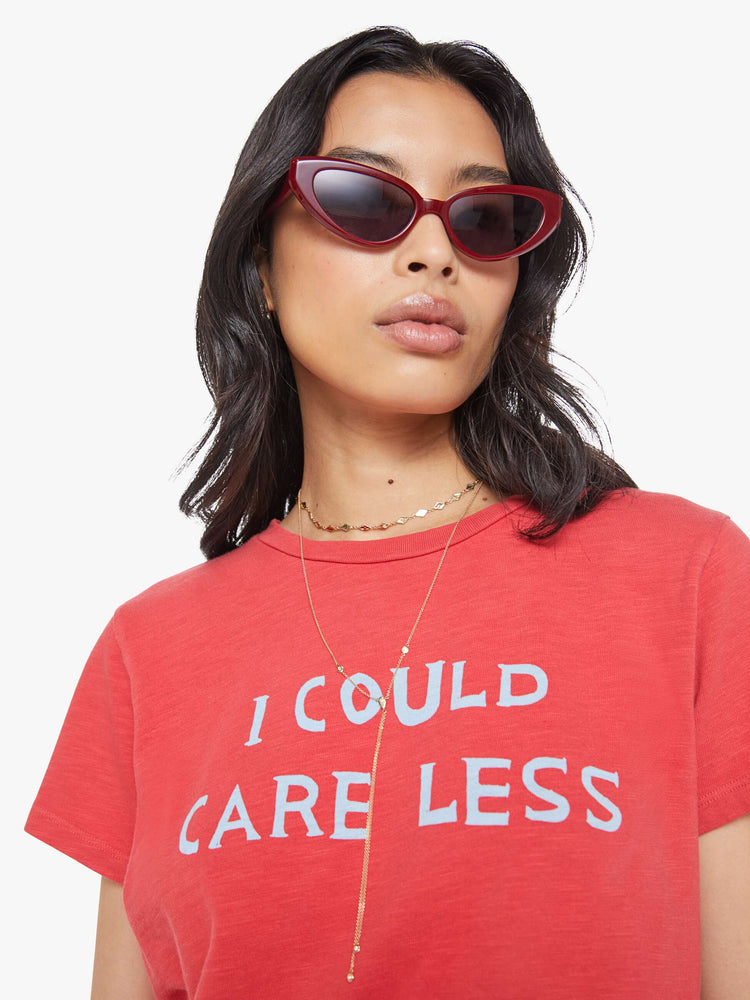 Close up view of a woman in a faded red tee with a white text graphic on the front.