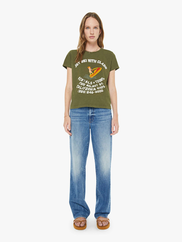 Full body view of a woman in an olive green, the tee with a jets ski school graphic with text in white on the front.