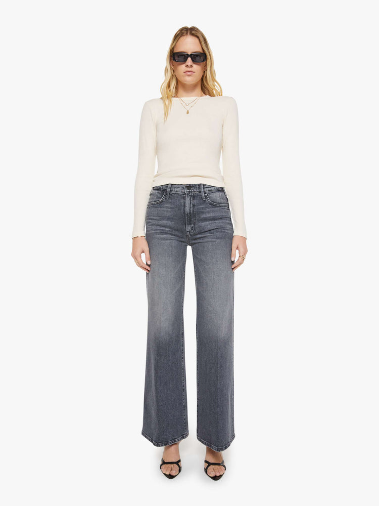Full body view of a woman in an off white crewneck top with long sleeves and a cropped fit.
