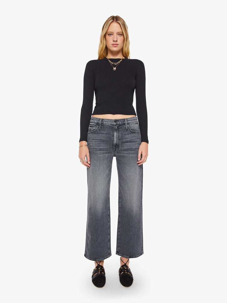 Full body view of a woman in a black shrunken crewneck tee with long sleeves and a cropped length.