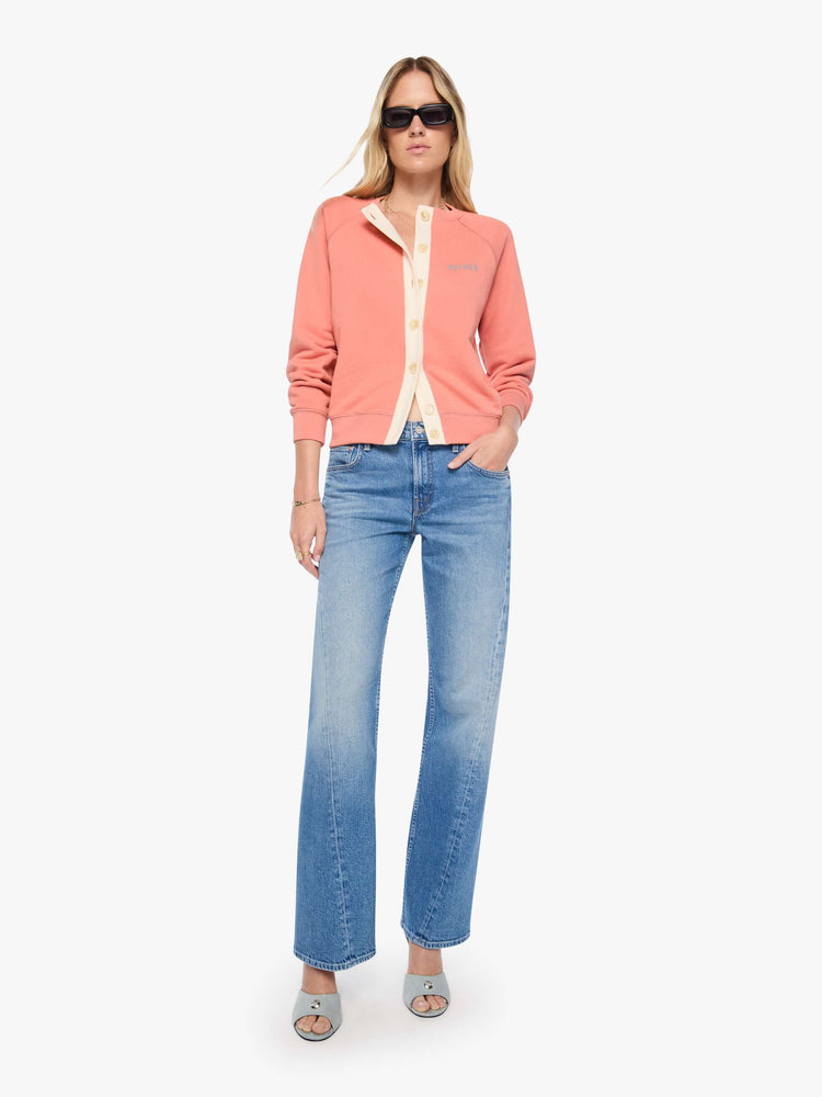 Full body view of a woman  pale pink cardigan features a cream button panel and a golden tiger graphic on the back, and MOTHER's name in light blue on the chest.
