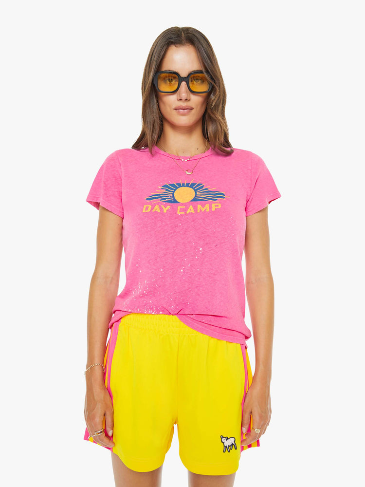 Front view of a woman in a pink with white paint splatters and a sun graphic on the front that reads "Day Camp."