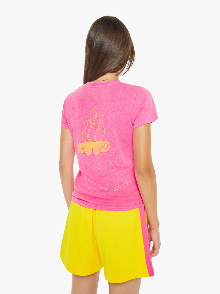 Back view of a woman in a pink with white paint splatters and a sun graphic on the front that reads "Day Camp."