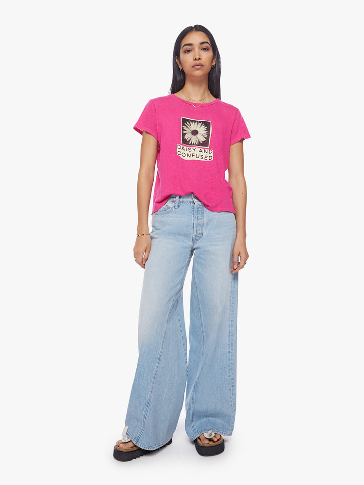 Full body view of a woman crewneck in a hot pink hue, the tee features a high-contrast daisy graphic and text on the front.