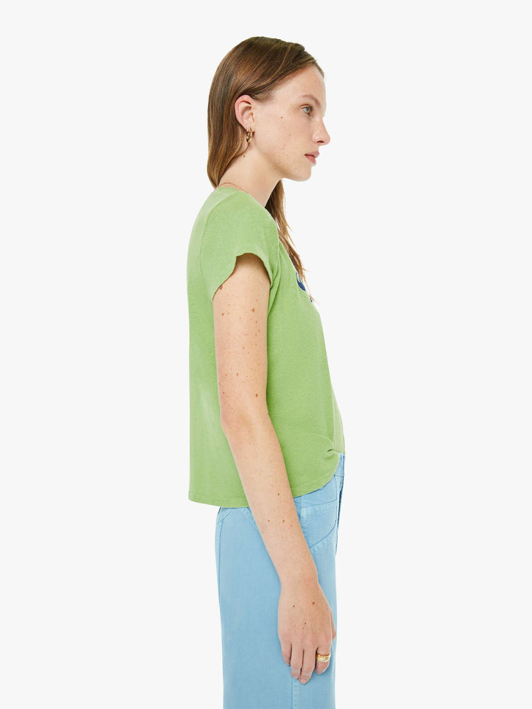 Side view of a woman in a tee is designed in green with a blue text graphic on the front that reads "Trinket Girl."