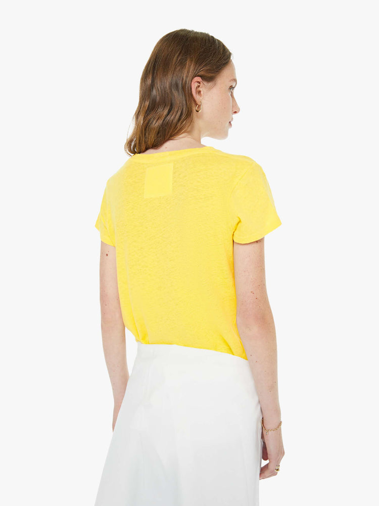 Back view of a woman in a yellow tee with a red apple graphic and MOTHER's name in blue on the front.