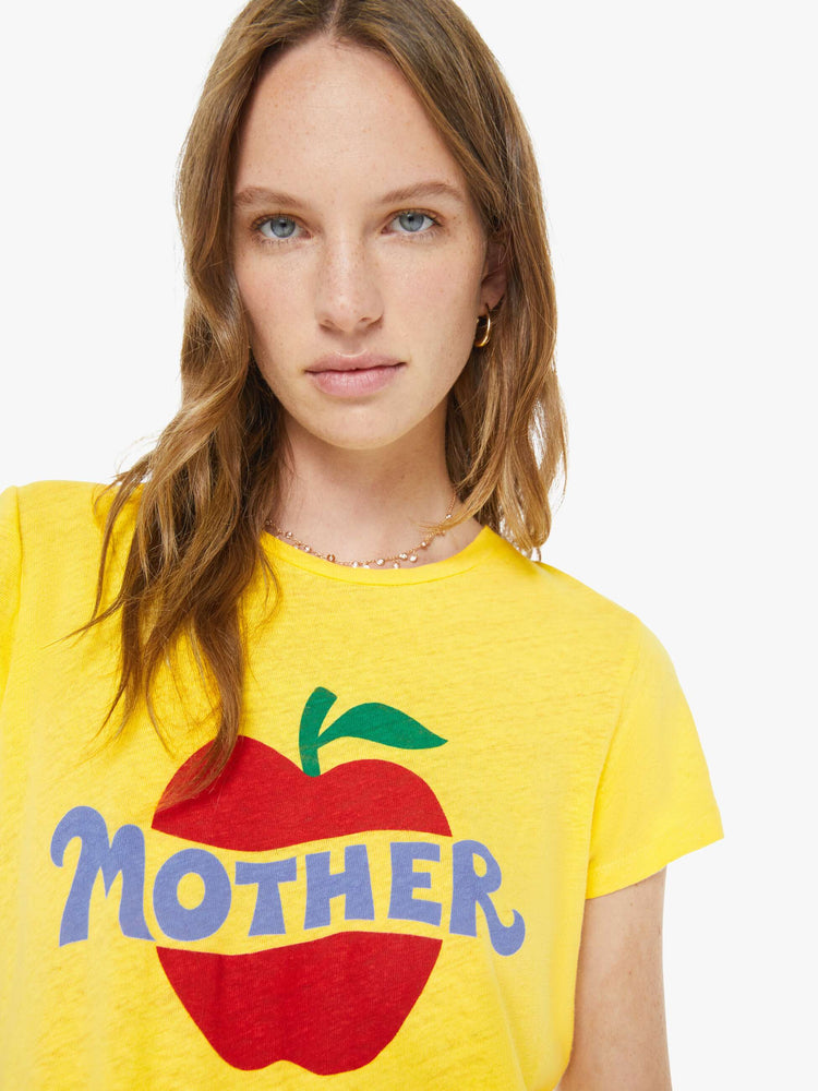 Close up view of a woman in a yellow tee with a red apple graphic and MOTHER's name in blue on the front.