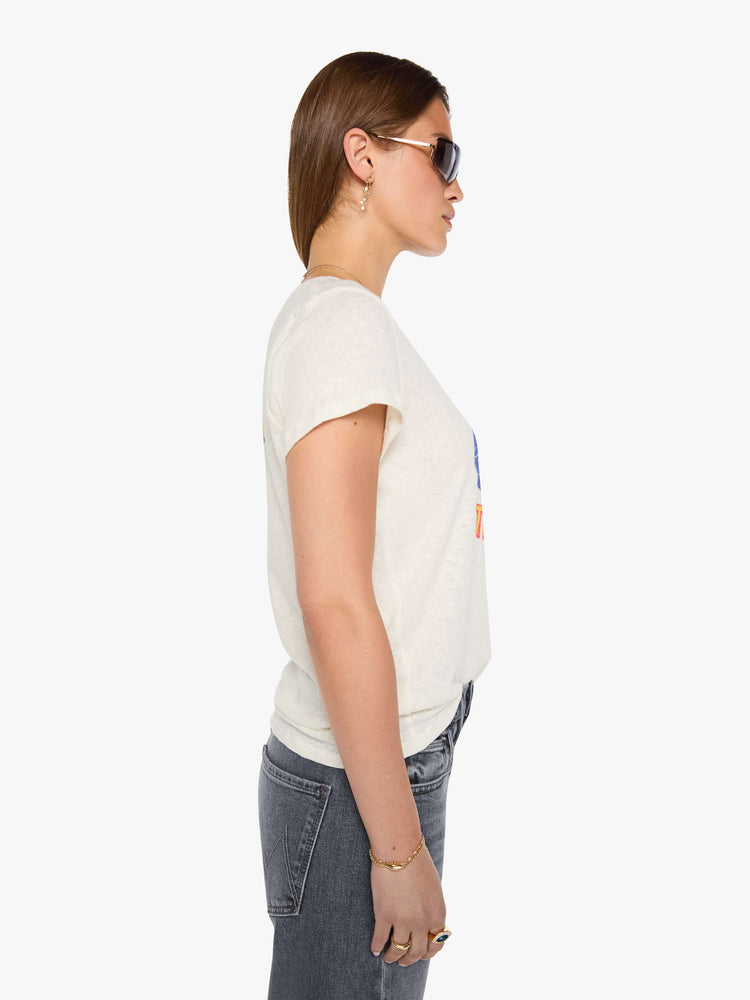 Side view of a woman in an off-white tee with a vintage-inspired globe graphic and text in yellow and pink on the front.