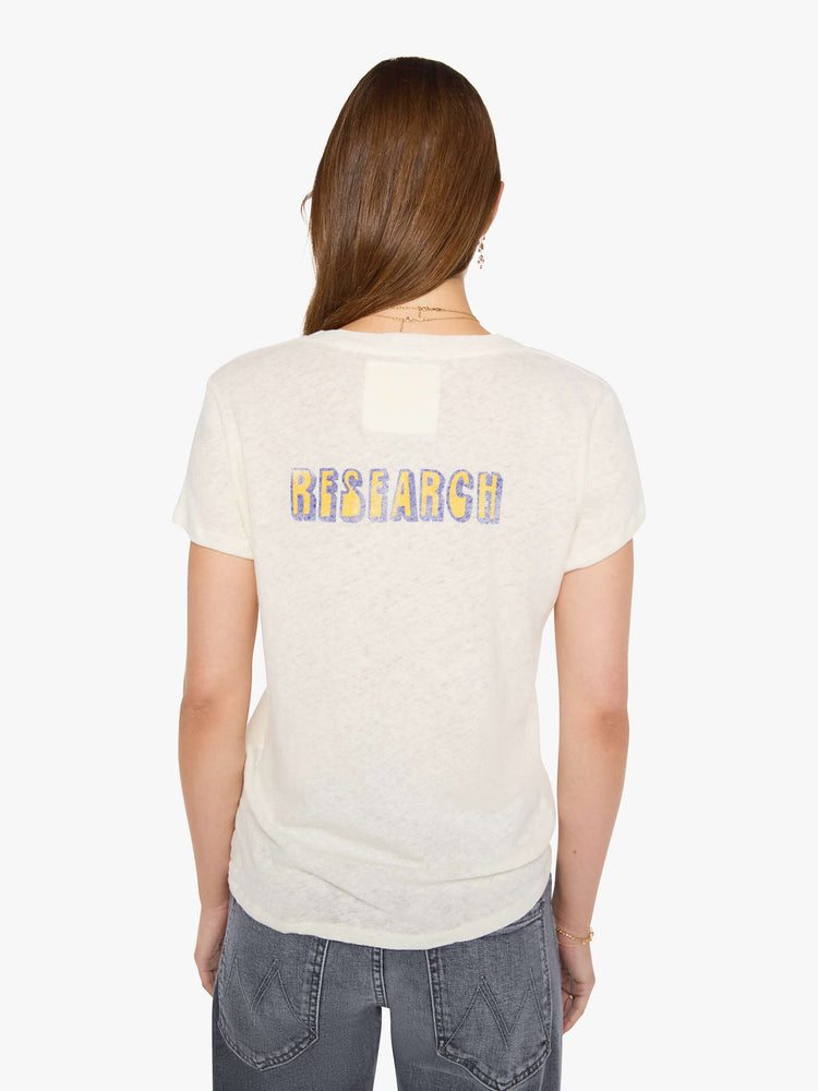 Back view of a woman in an off-white tee with a vintage-inspired globe graphic and text in yellow and pink on the front.