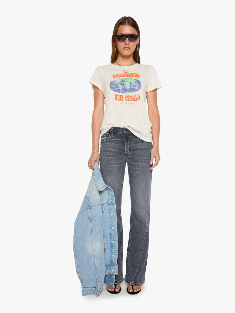 Full body view of a woman in an off-white tee with a vintage-inspired globe graphic and text in yellow and pink on the front.