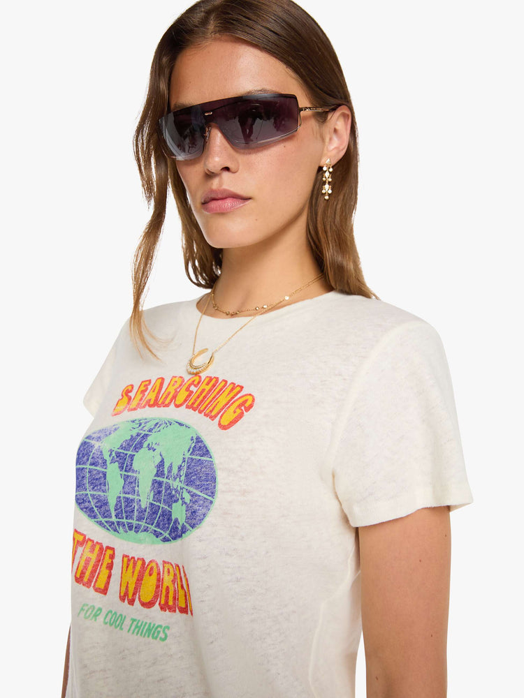Close up view of a woman in an off-white tee with a vintage-inspired globe graphic and text in yellow and pink on the front.