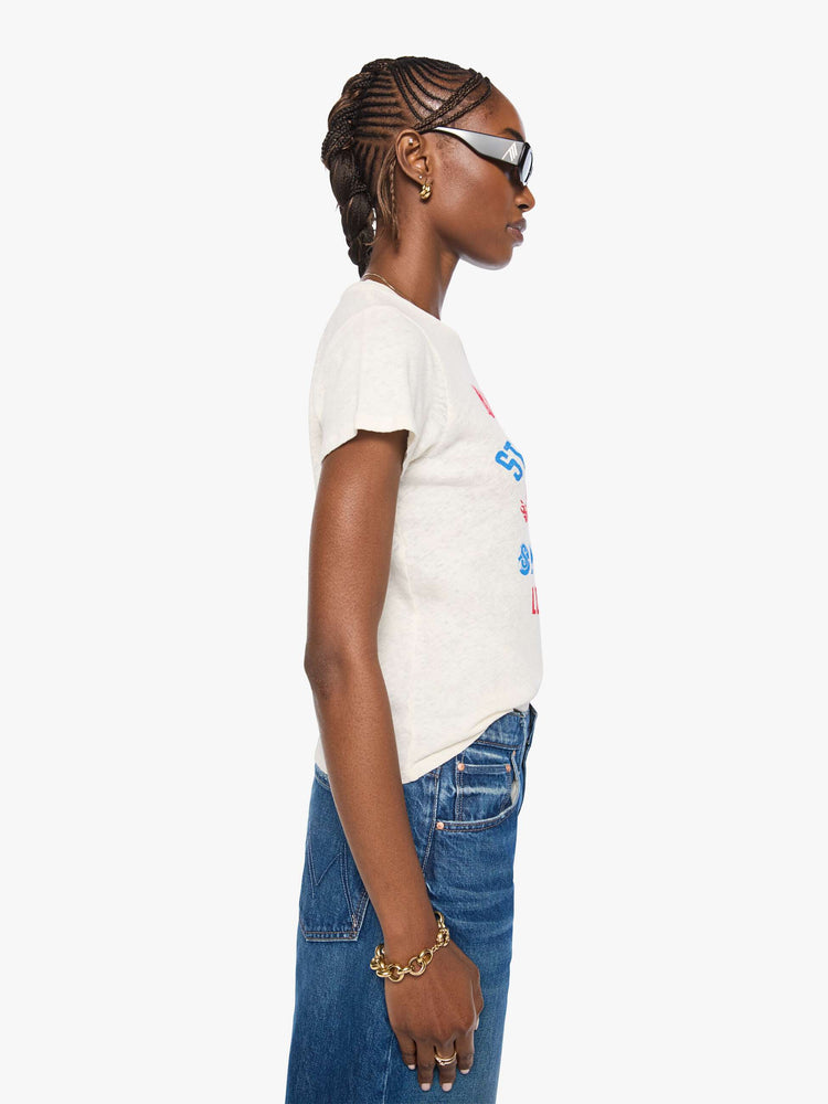 Side view of a woman in an off-white with a vintage-inspired speedway graphic and text in red and blue on the front.