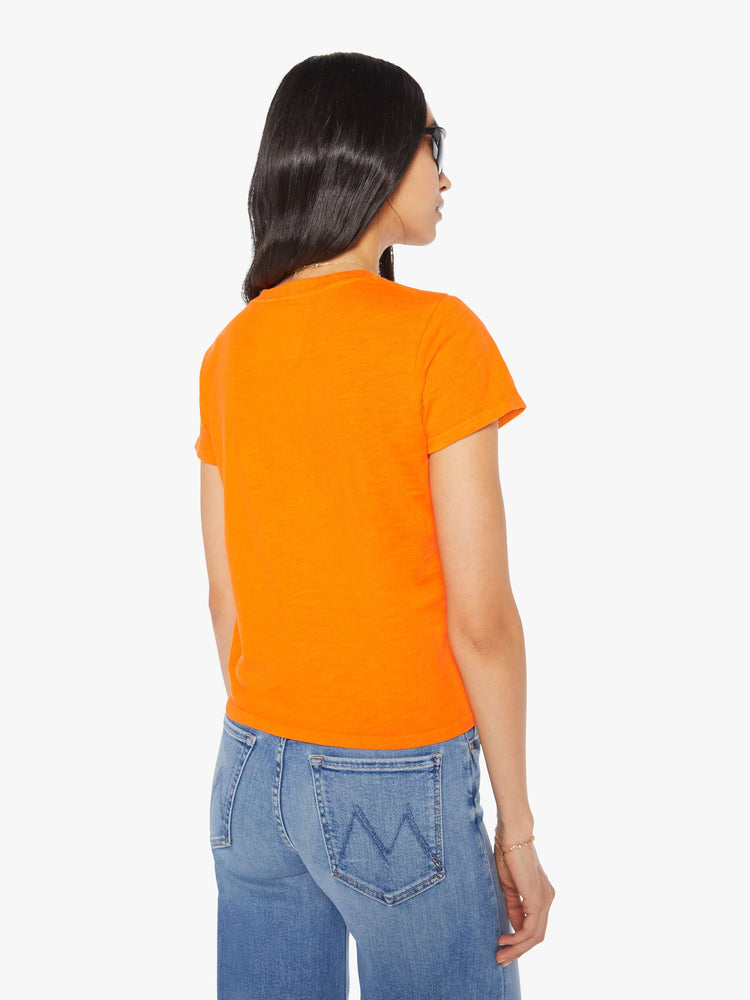 Back view of a woman in a bright orange tee with a blue graphic on the front that reads "trucks are for girls".