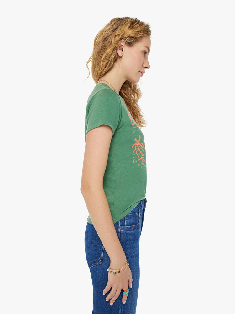 Side view of a woman in a forest green crewneck with a slim fit featuring a hand drawn text graphic "Bon Voyage" in peach styled with blue jeans.