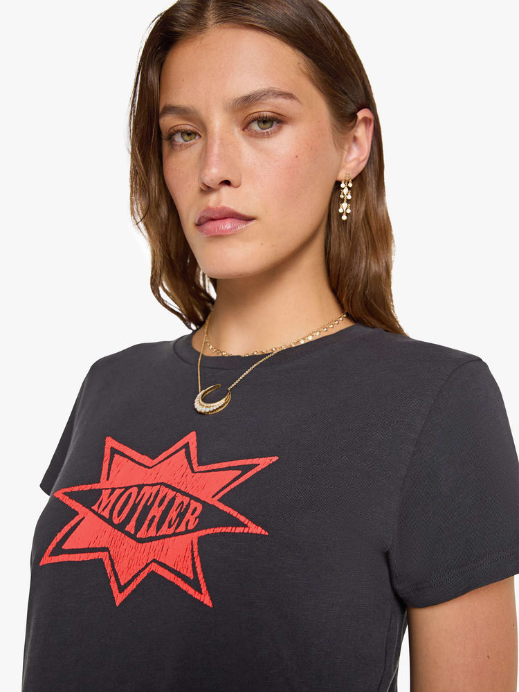 Close up view of a woman in a faded black tee with MOTHER's name in a coral crackle-printed starburst graphic on the front.