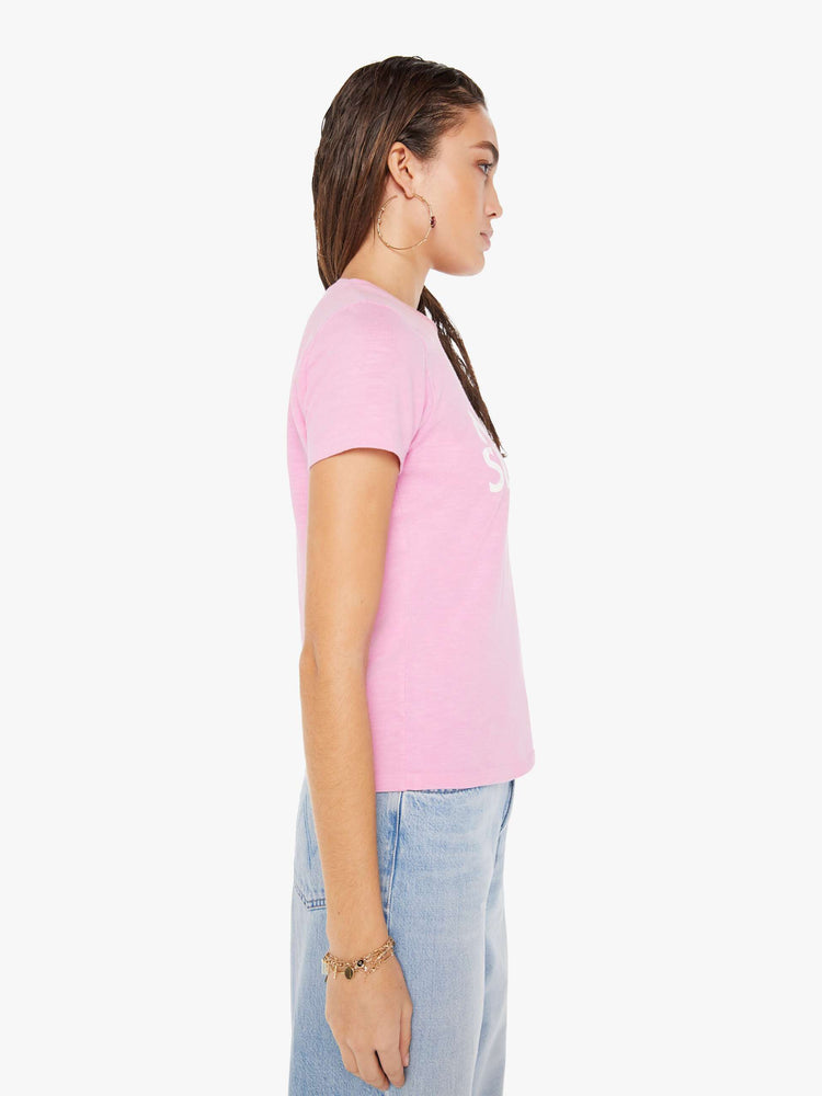 Side view of a woman wearing a fitted pink crew neck tee, paired with a light blue wash jean.