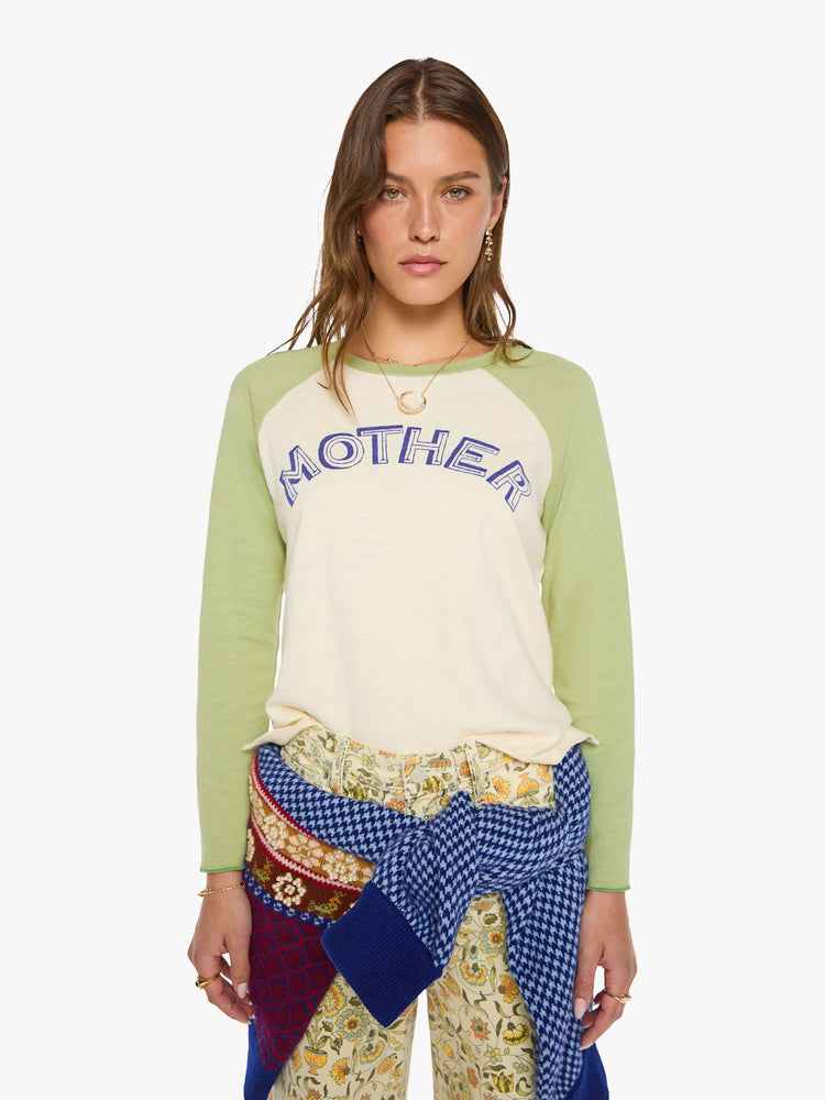 Front view of a woman in a vintage concert tee in off-white with light green sleeves and MOTHER's name in navy block text across the chest.