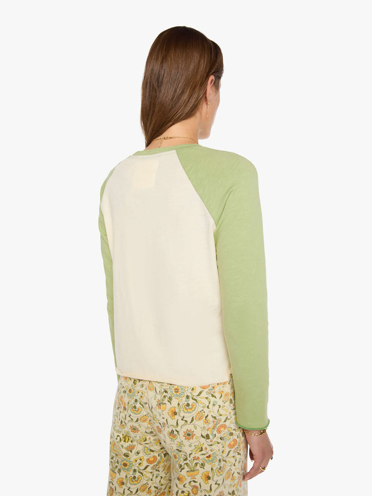 Back view of a woman in a vintage concert tee in off-white with light green sleeves and MOTHER's name in navy block text across the chest.