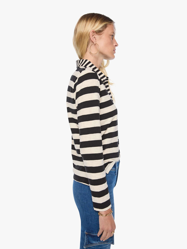 Side view of a woman in black and cream stripes long sleeve top features a fuzzy lamb patch on the chest.