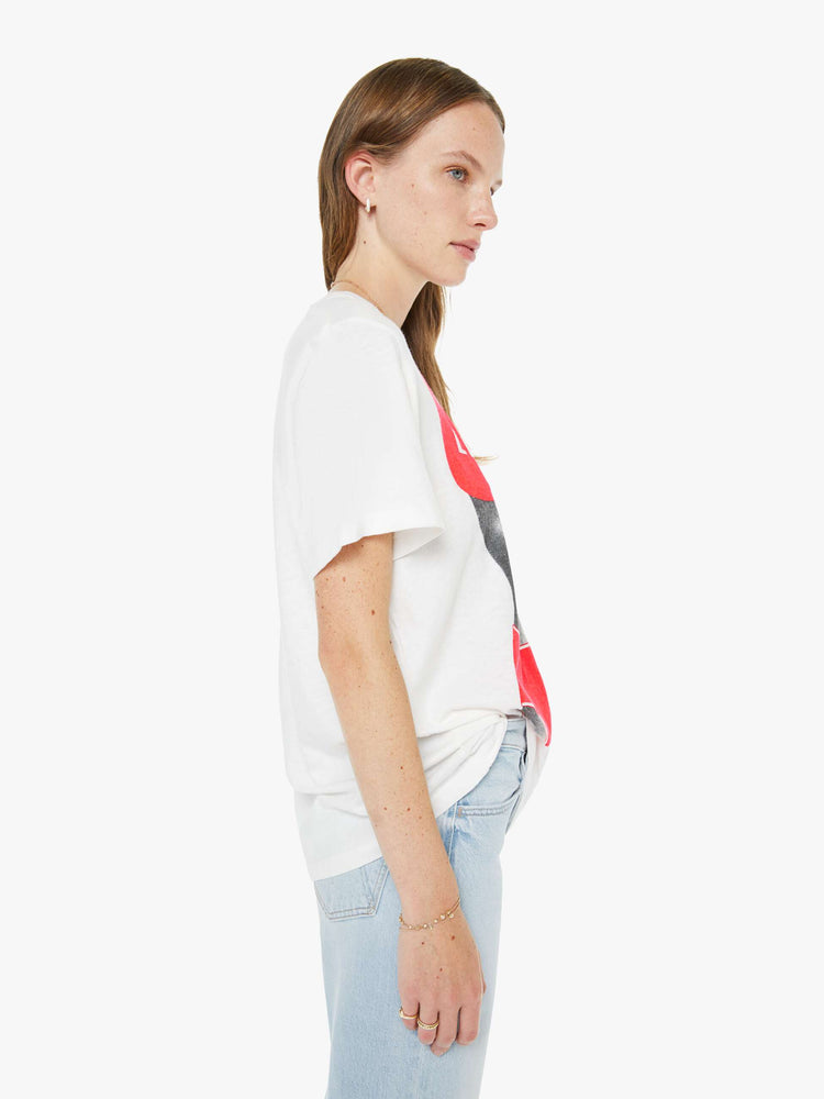 Side view of a woman in a white tee with a black-and-white silhouette wearing an orange lifeguard bikini on the front.