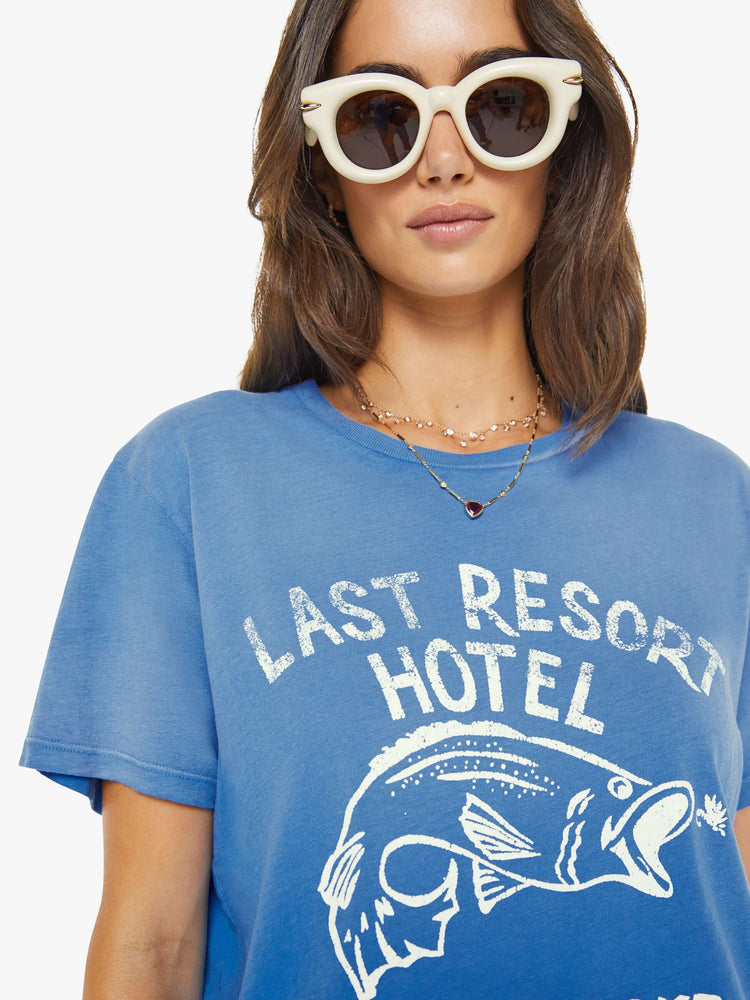 Close up view of a woman in faded blue tee with a white fish and lure graphic with text on the front.