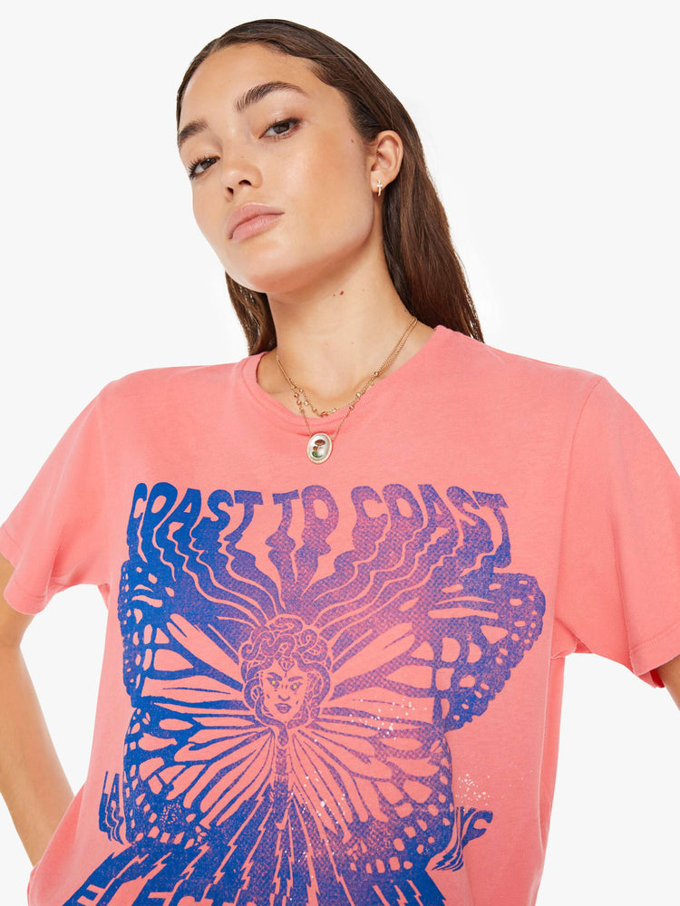 Front close up view of a womens pink crew neck tee featuring a large blue graphic.