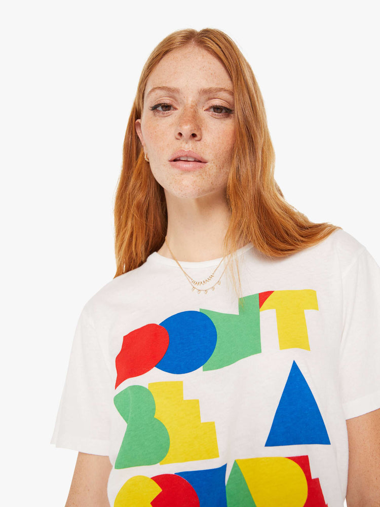 Close up view of a woman white oversized crewneck tee with overlapping shades of red, blue, green and yellow on front.