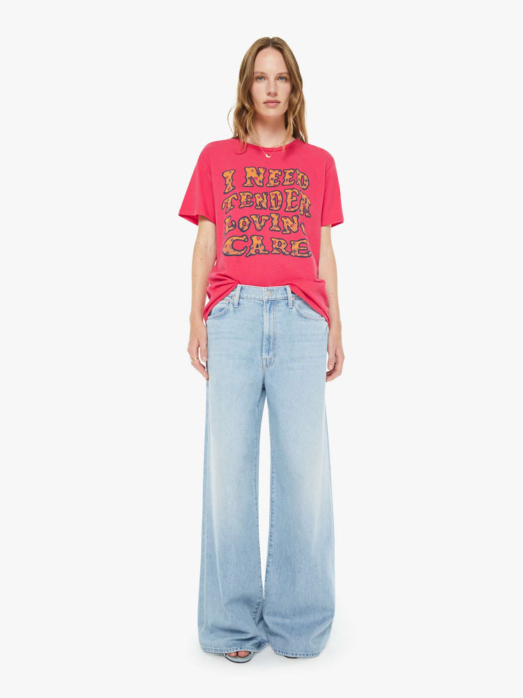 Full body view of a woman in a hot pink tee features a subtle message from MOTHER in oversized yellow block text on the front.