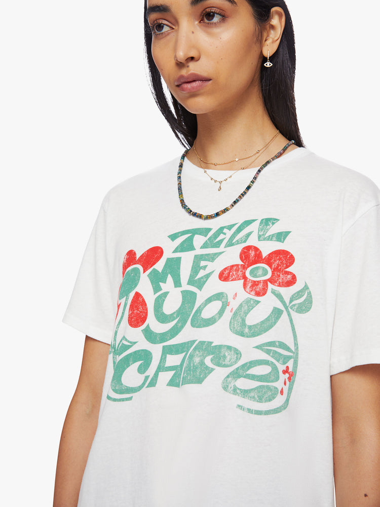 Close up view of a woman crewneck tee with an oversized fit in white with faded text graphic in green and red.