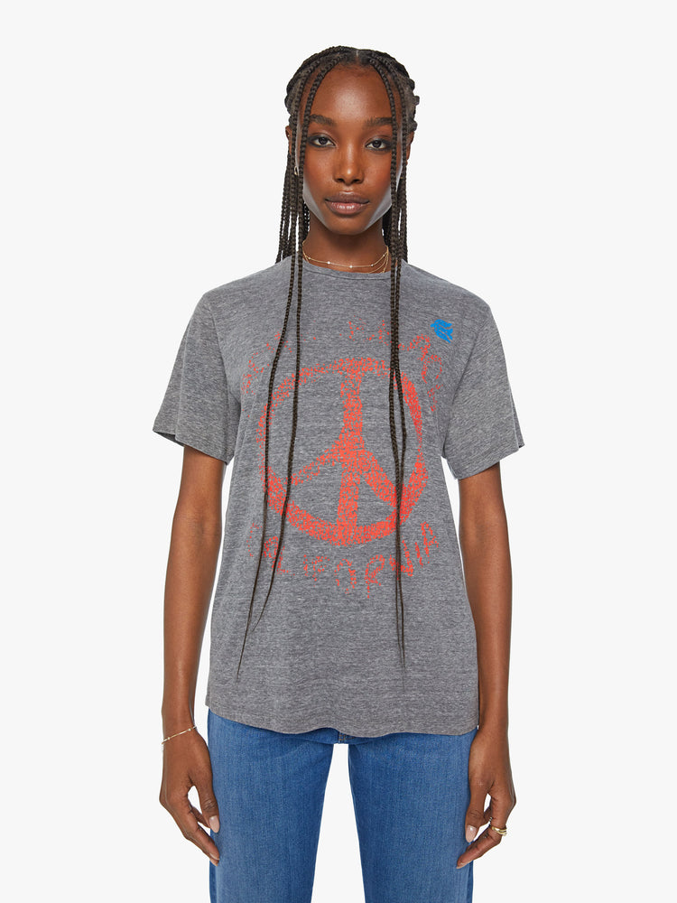Front view of a woman crewneck tee with an oversized fit and a clean hem in grey tee with a super-distressed orange peace sign and faded text on the front.