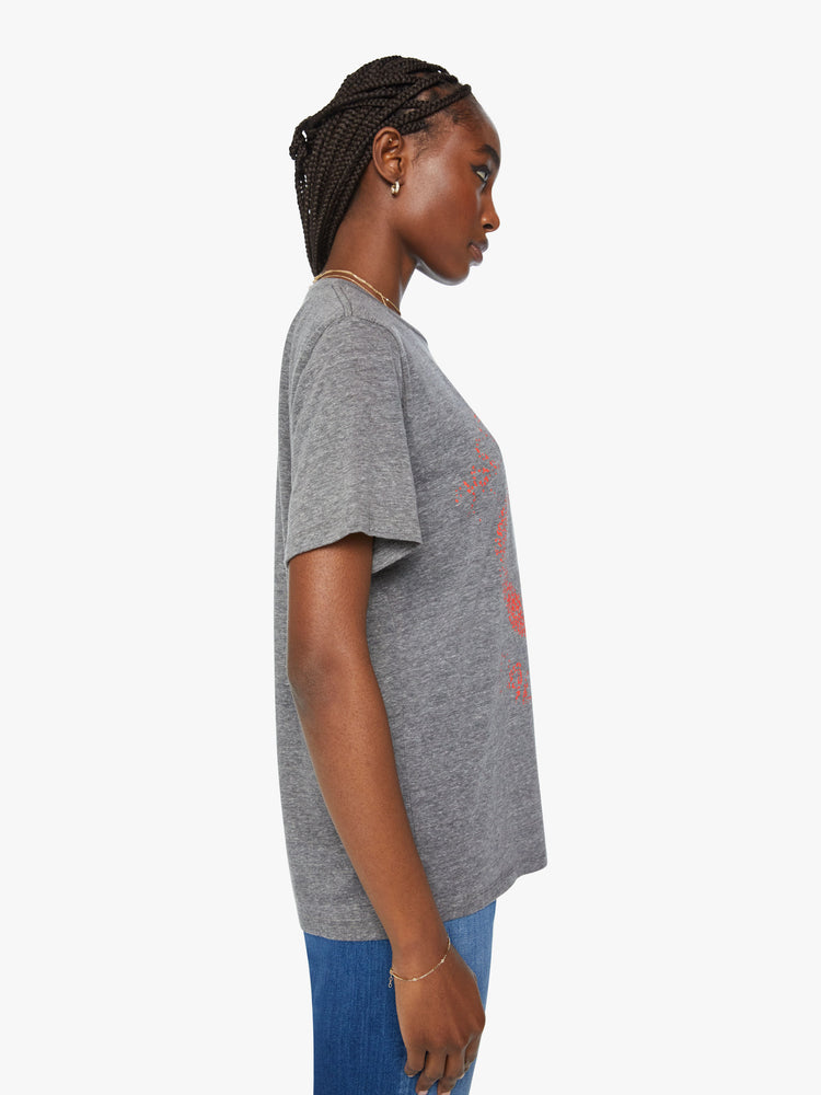 Side view of a woman crewneck tee with an oversized fit and a clean hem in grey tee with a super-distressed orange peace sign and faded text on the front.