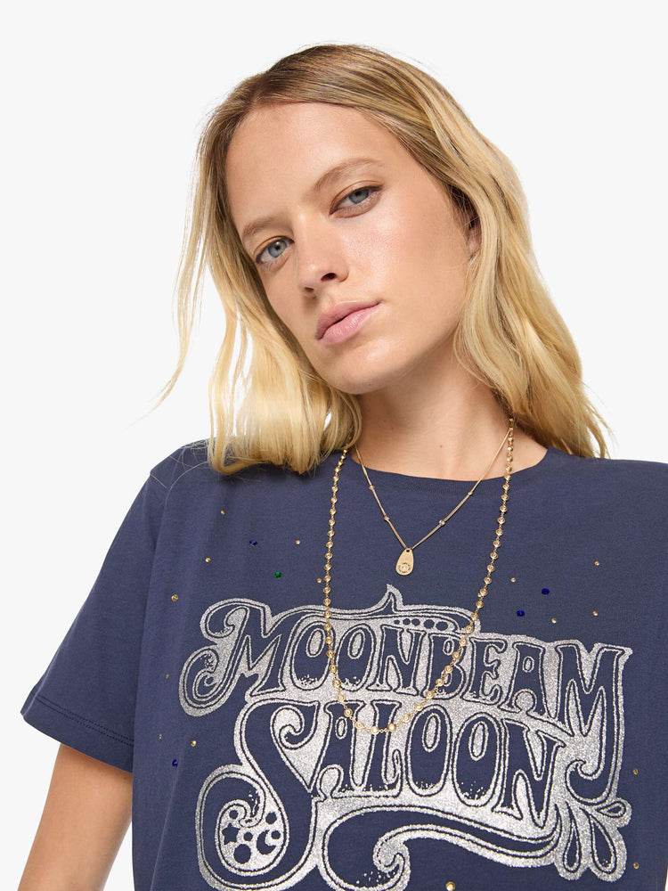 Close up view of a woman in dark navy tee with a faded text graphic in white on the front, rhinestone details and MOTHER's name in studs on the back.